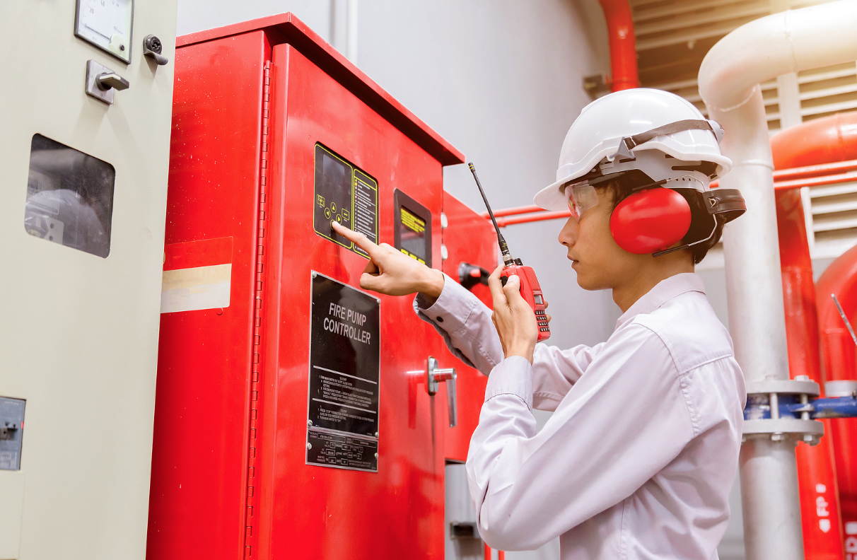 Inspector wearing a hard hat checking an industrial fire alarm